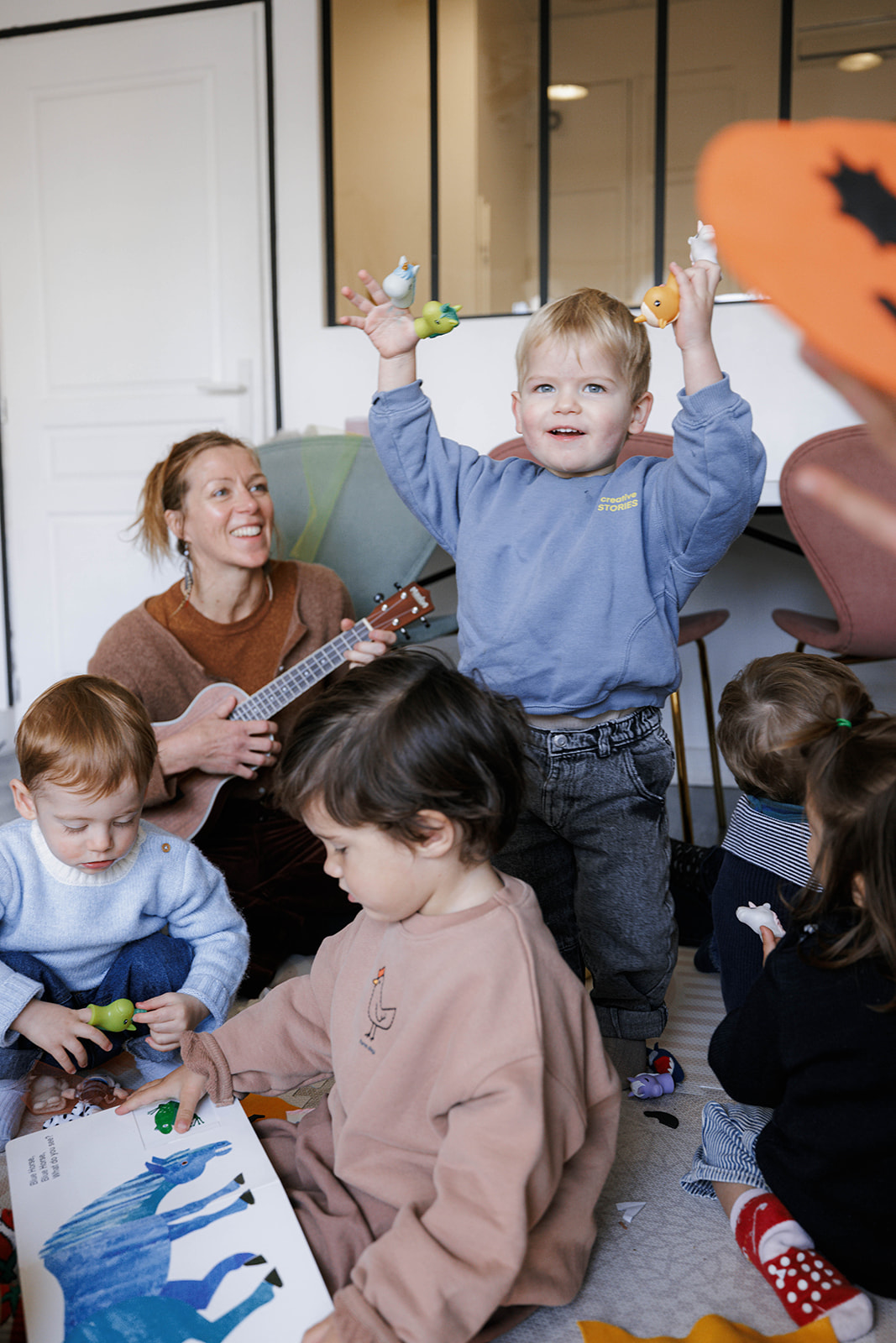 Enfant est assis sur le sol et joue avec des jouets, tandis qu'une autre enfant, penché en avant, regarde un livre. Trois ...